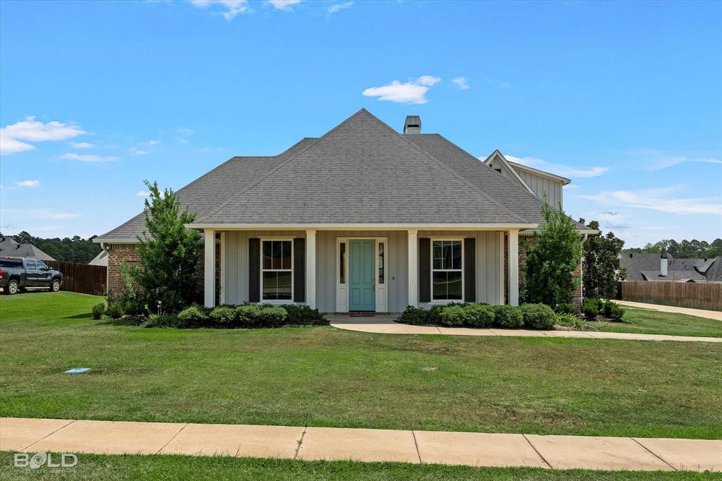 143 Oak Alley Road Stonewall, LA 71078 - Photo 1 of 38 Single-story residence featuring a gabled roof, brick and board-and-batten siding, a covered entry with columns, and a light blue front door