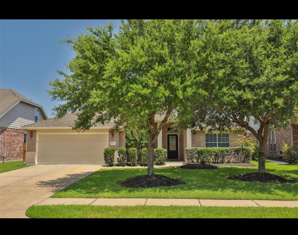 a view of house in front of a big yard with large trees