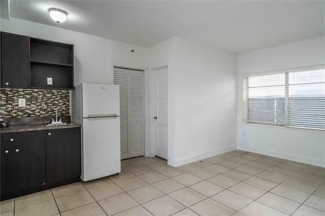 a view of kitchen with a sink refrigerator and window