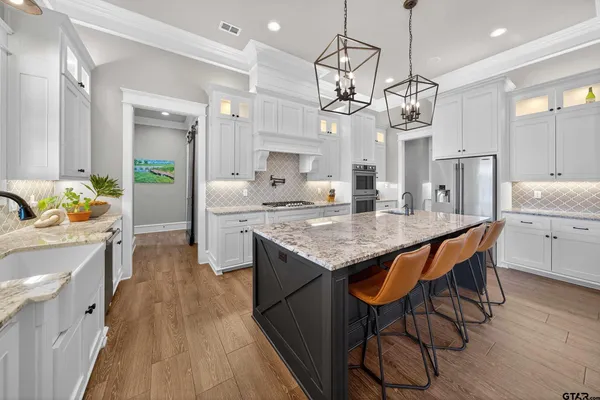 a open kitchen with granite countertop a stove a sink a center island and wooden floor