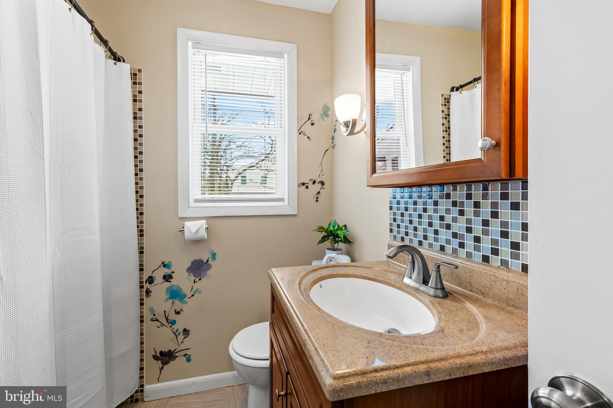127 Cresston Road Arnold, MD 21012 - Photo 19 of 32 a bathroom with a granite countertop toilet a sink a mirror a window and a shower