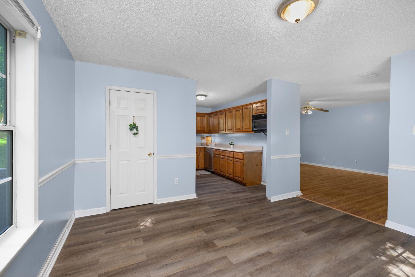 366 Adkins Road Burlison, TN 38015 - Photo 5 of 20 Open concept living area featuring wood-finish flooring, light blue walls with chair rail molding, and a kitchen with wood cabinetry and a built-in microwave