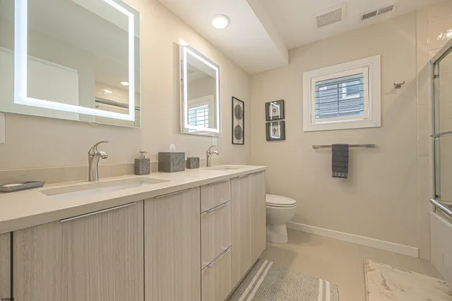 a bathroom with a toilet a sink a mirror and a shower