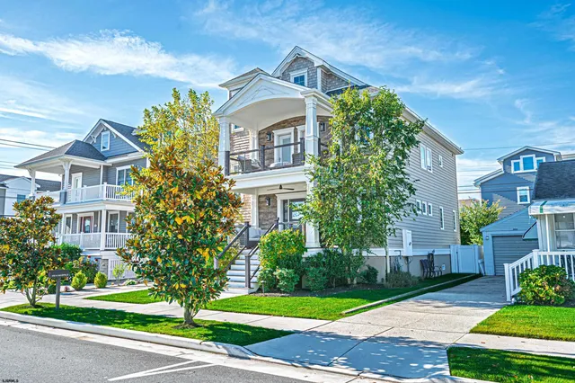 a front view of a multi story residential apartment building with yard and green space
