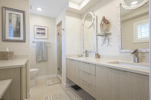 a bathroom with a double vanity sink mirror and toilet