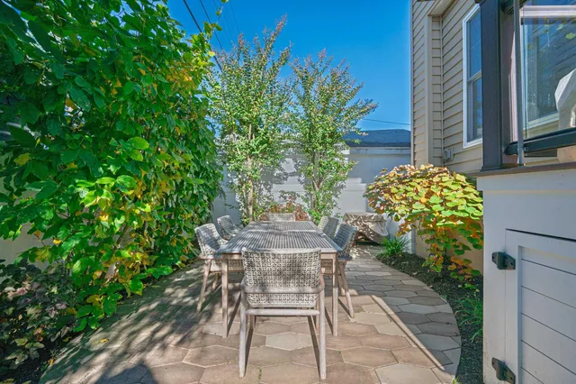 a patio with table and chairs and potted plants