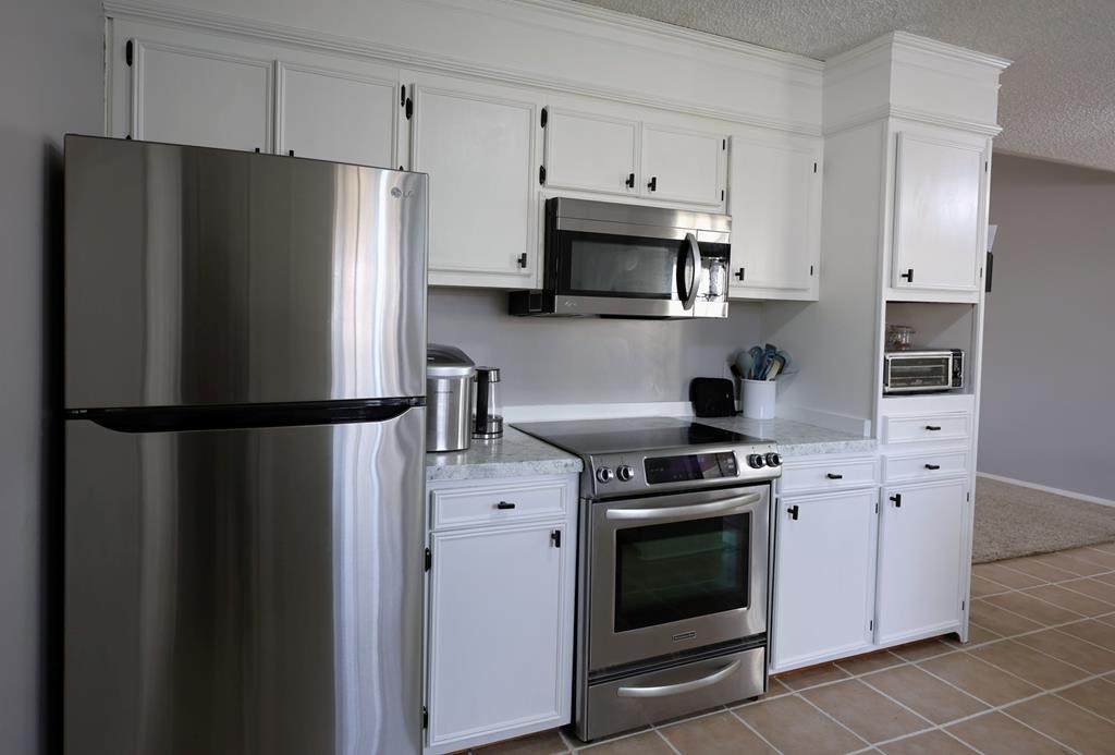 235 Spring Branch Street Lufkin, TX 75904 - Photo 10 of 30 a kitchen with stainless steel appliances a refrigerator a stove and white cabinets