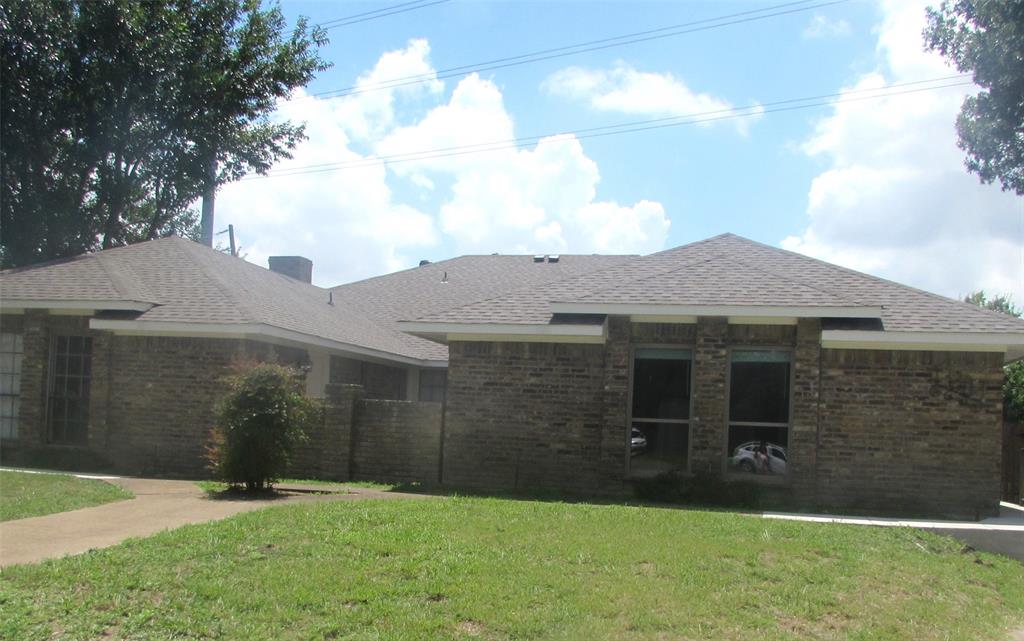 Back of house featuring brick siding, a yard, and roof with shingles