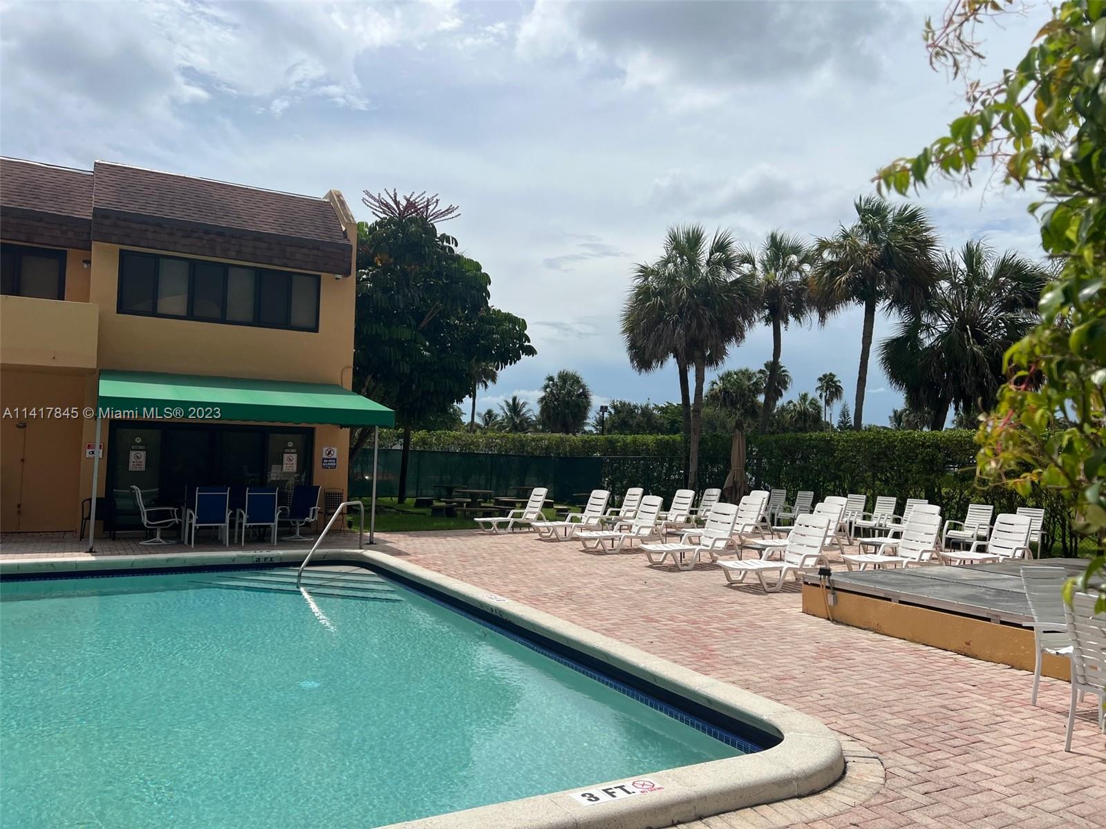 450 Commodore Drive, Unit 211 Plantation, FL 33325 - Photo 12 of 12 a view of a swimming pool with a lawn chairs under palm trees