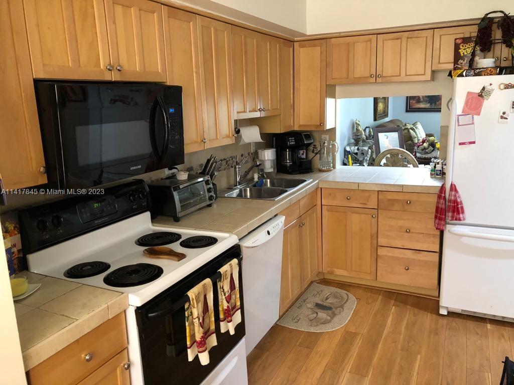 450 Commodore Drive, Unit 211 Plantation, FL 33325 - Photo 4 of 12 a kitchen with a sink a stove and cabinets