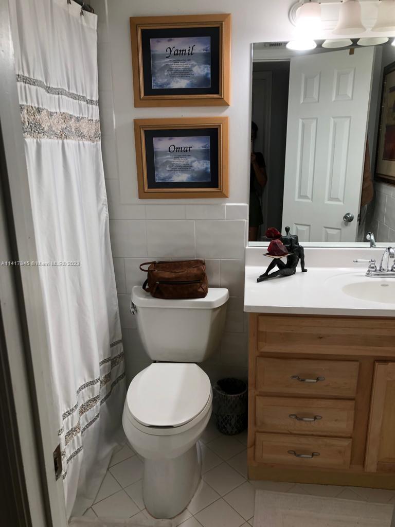 450 Commodore Drive, Unit 211 Plantation, FL 33325 - Photo 7 of 12 a bathroom with a toilet a sink and a mirror
