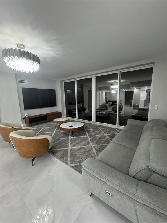 2051 Southeast 3rd Street, Unit 406 Deerfield Beach, FL 33441 - Photo 24 of 61 a living room with furniture a chandelier and a flat screen tv