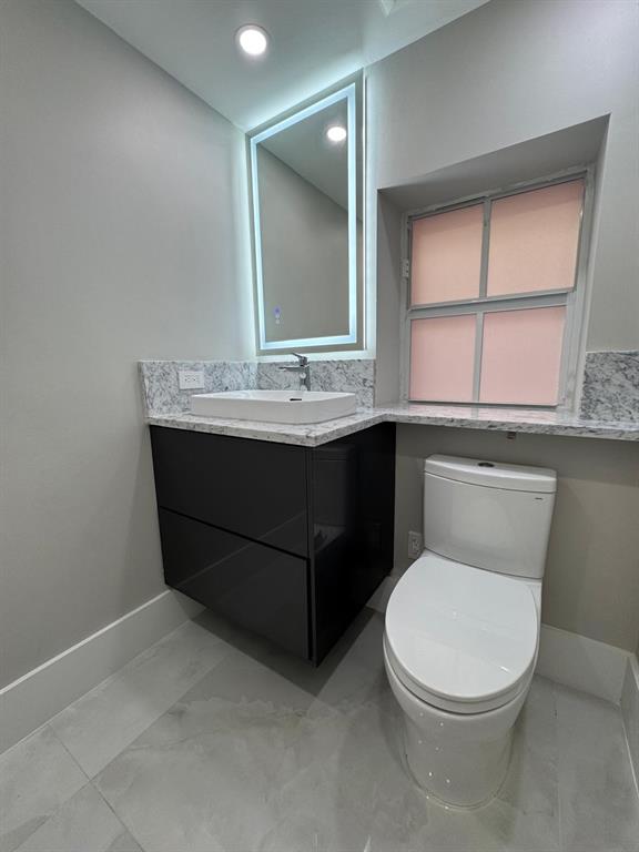 2051 Southeast 3rd Street, Unit 406 Deerfield Beach, FL 33441 - Photo 26 of 61 a bathroom with a toilet a sink and mirror