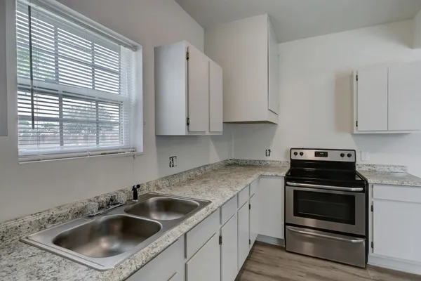 a kitchen with white cabinets a sink and appliances