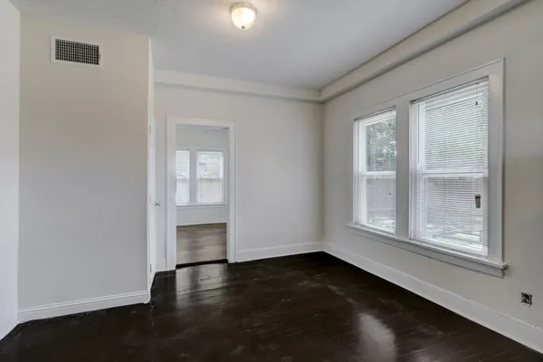an empty room with wooden floor and windows