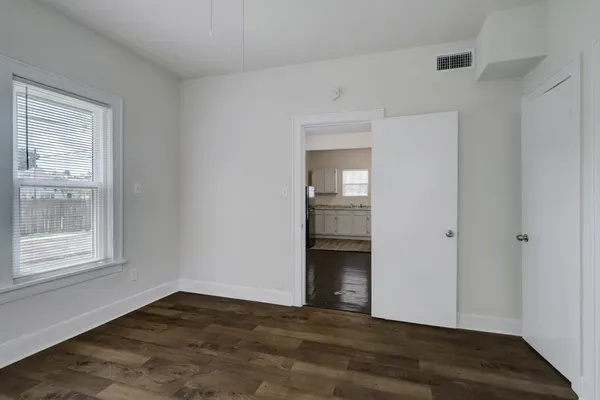 a view of an empty room with wooden floor and a window