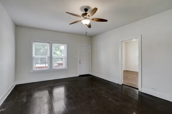 a view of an empty room with wooden floor and a window