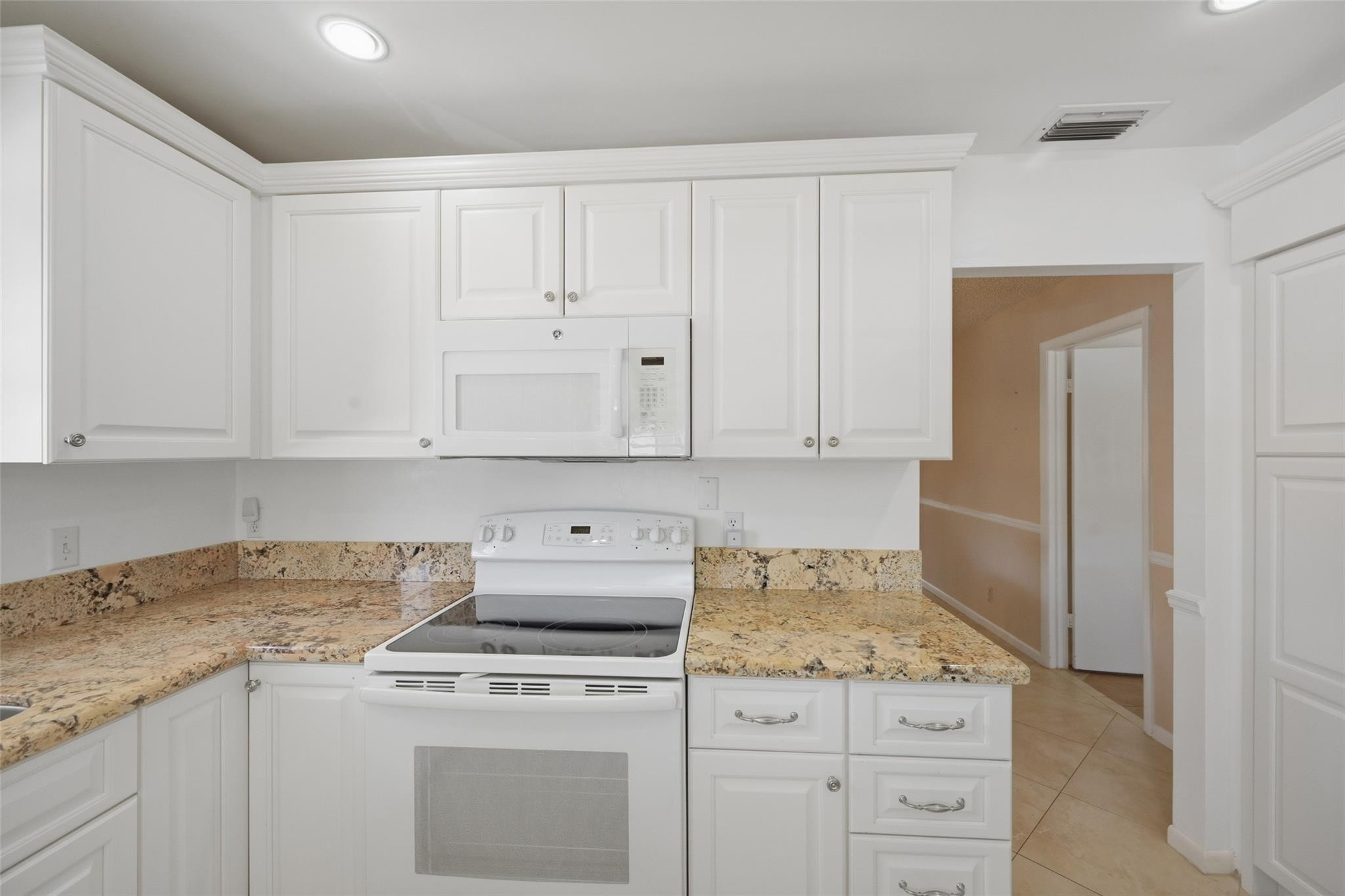 602 Hummingbird Lane, Unit 602 Delray Beach, FL 33445 - Photo 18 of 31 a kitchen with granite countertop white cabinets and white appliances