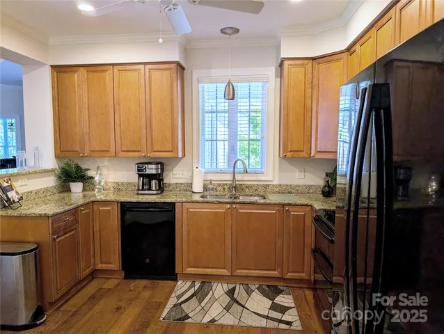 a kitchen with stainless steel appliances granite countertop a refrigerator a sink dishwasher and wooden cabinets with wooden floor