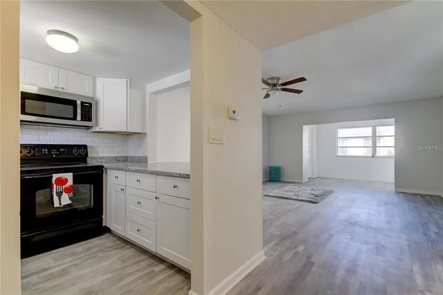 a view of kitchen and empty room with wooden floor
