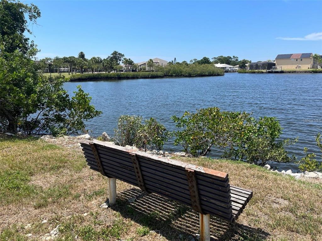 4901 Onyx Lane, Unit 204 New Port Richey, FL 34652 - Photo 39 of 46 a wooden bench sitting next to a lake view