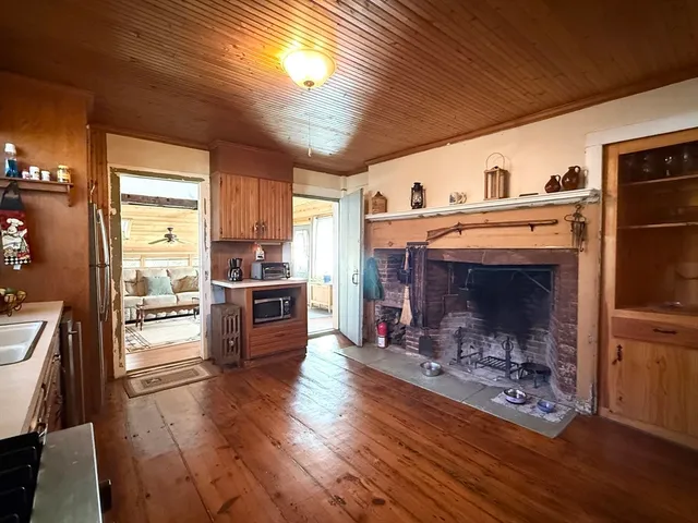 a kitchen with stainless steel appliances granite countertop a stove a refrigerator a sink a dining table and chairs with wooden floor