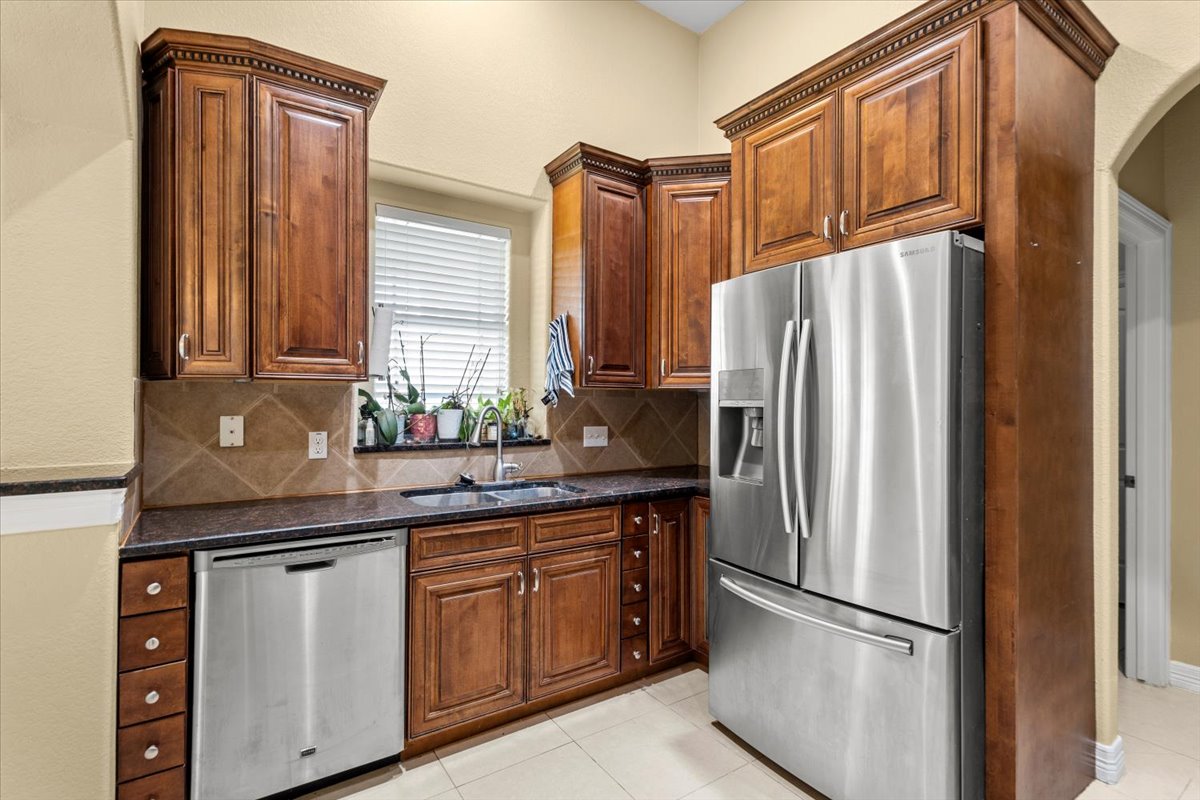 437 Balch Road Elgin, TX 78621 - Photo 9 of 37 Rich wood cabinetry and stainless steel appliances elevate this functional kitchen space.