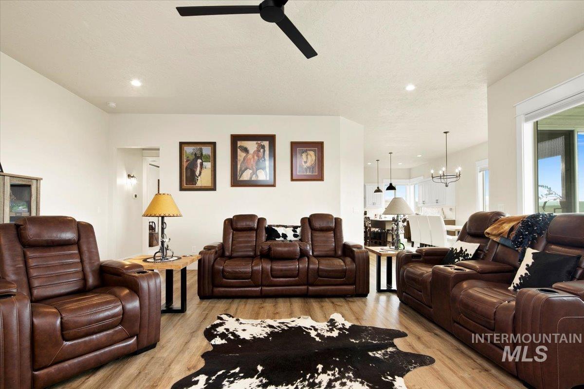 6721 El Paso Road Caldwell, ID 83607 - Photo 11 of 50 Living room with light wood-style floors, a chandelier, a ceiling fan, a textured ceiling, and recessed lighting