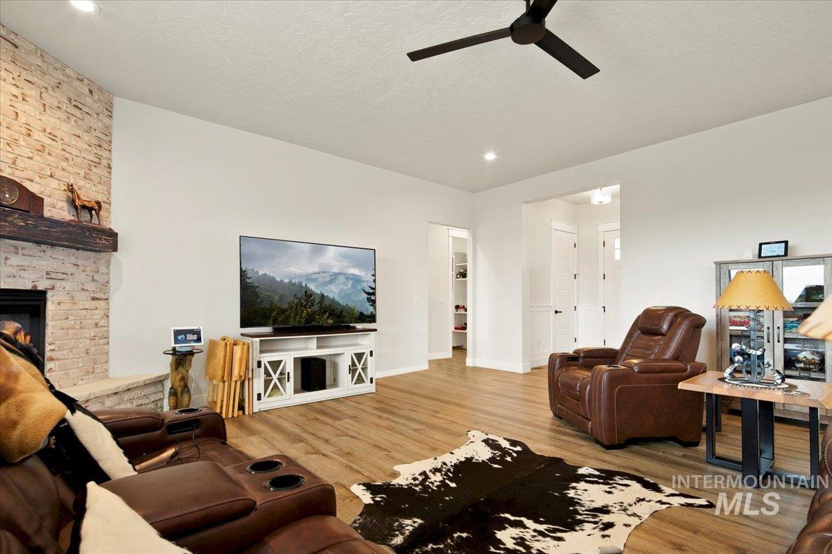 6721 El Paso Road Caldwell, ID 83607 - Photo 12 of 50 Living room featuring wood finished floors, a fireplace, a textured ceiling, and a ceiling fan