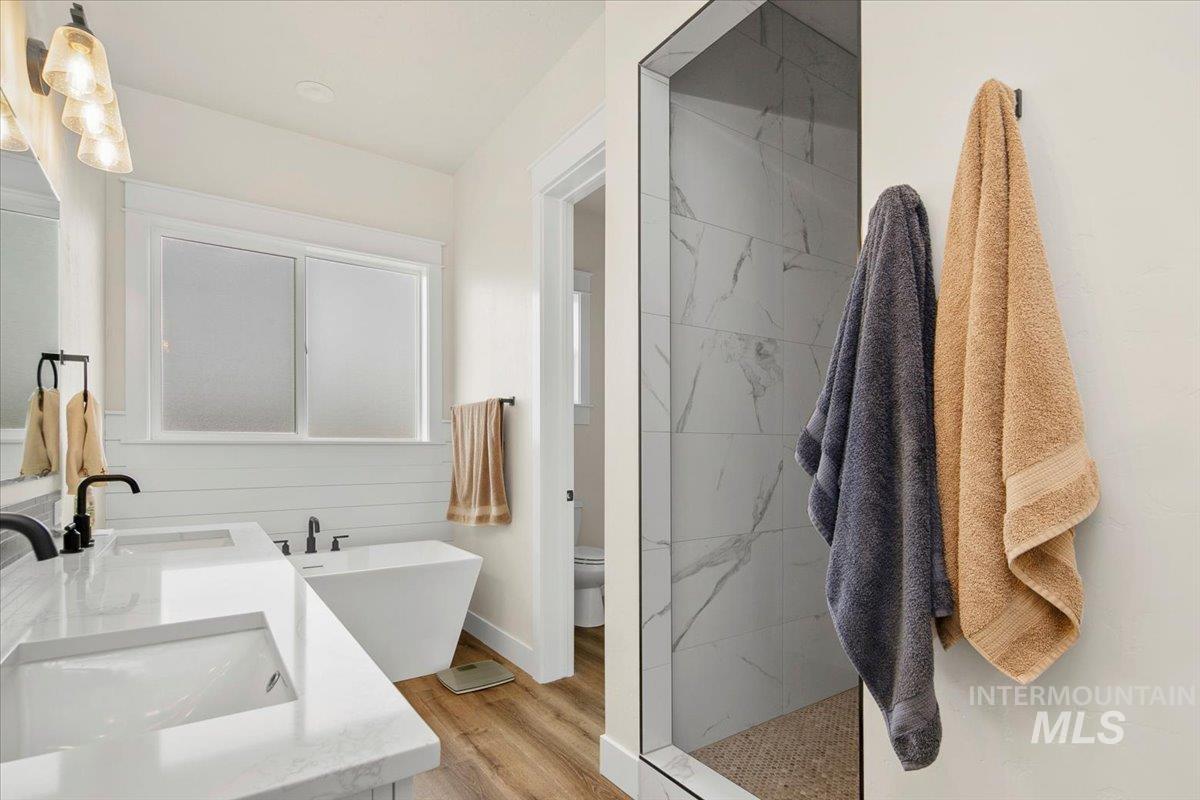 6721 El Paso Road Caldwell, ID 83607 - Photo 25 of 50 Full bathroom featuring double vanity, light wood-style flooring, a freestanding bath, and a marble finish shower