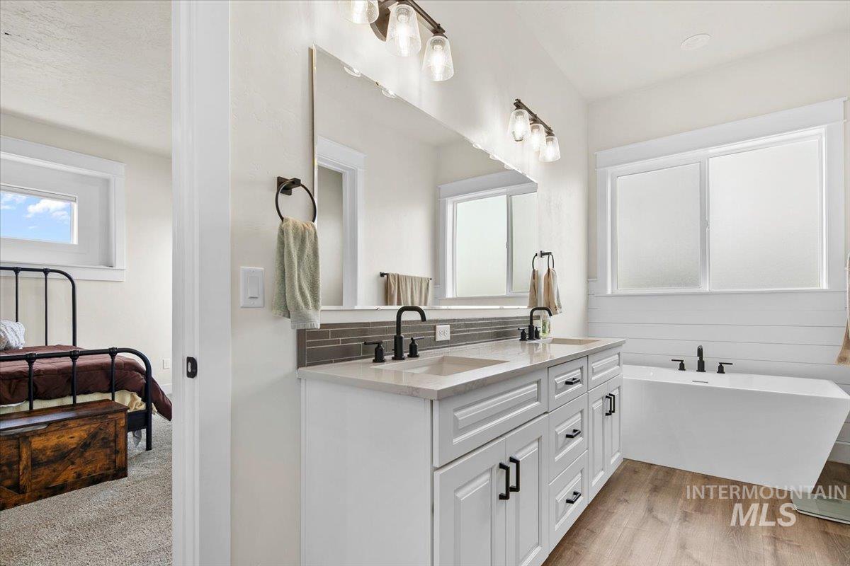 6721 El Paso Road Caldwell, ID 83607 - Photo 26 of 50 Ensuite bathroom with double vanity, a freestanding bath, light wood finished floors, and decorative backsplash