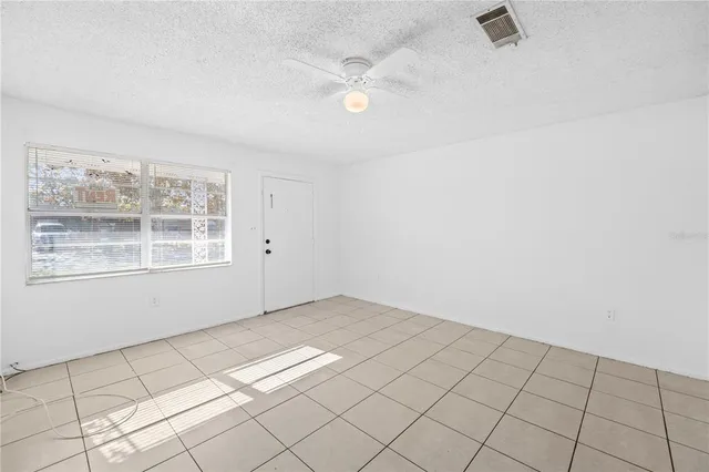 an empty room with windows and fan