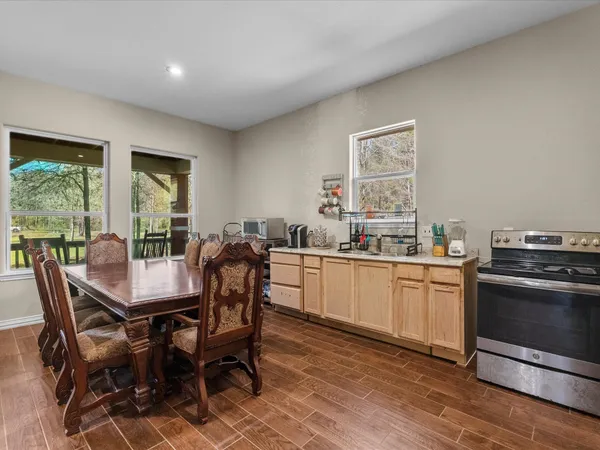 a dining hall with stainless steel appliances granite countertop a stove a sink a dining table and chairs