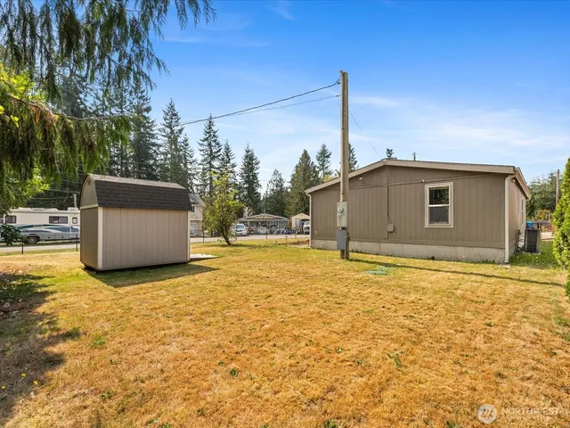 a backyard of a house with large trees and wooden fence
