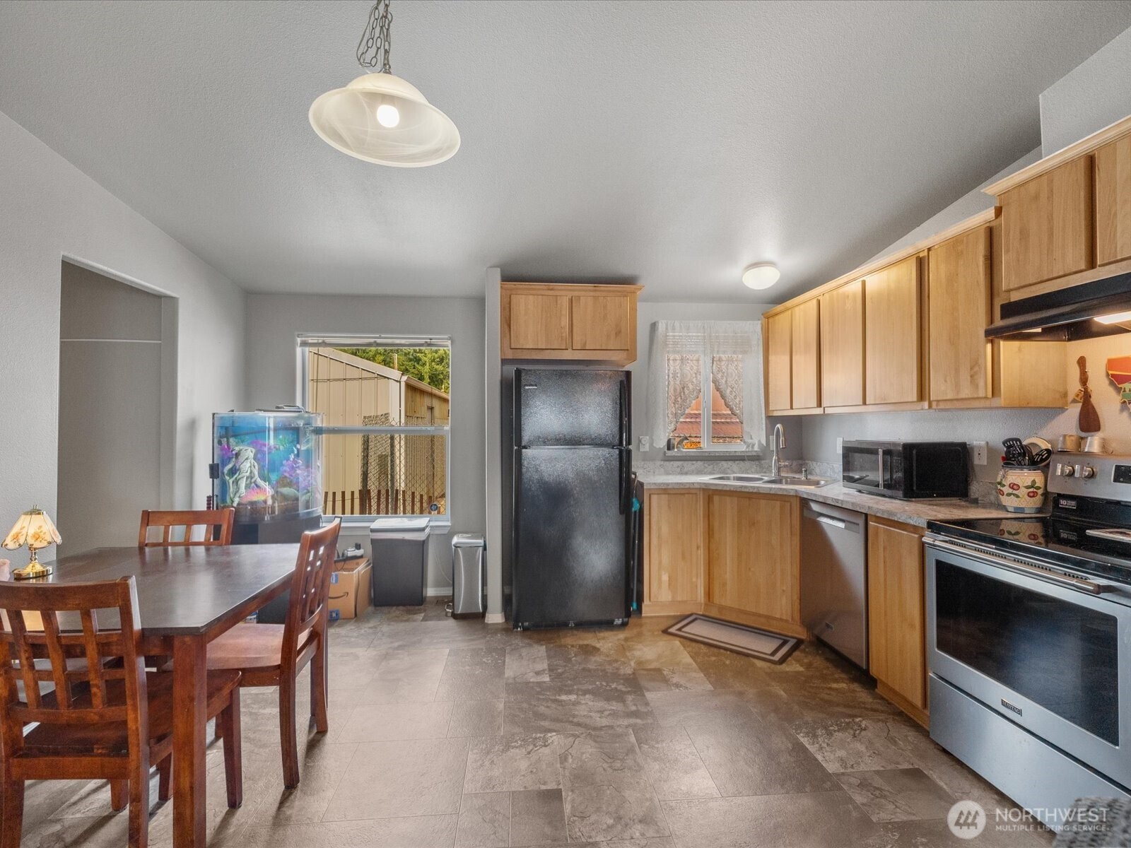 12721 West Macs Loop Road Granite Falls, WA 98252 - Photo 8 of 31 a kitchen with stainless steel appliances granite countertop a refrigerator a stove a sink a dining table and chairs with wooden floor