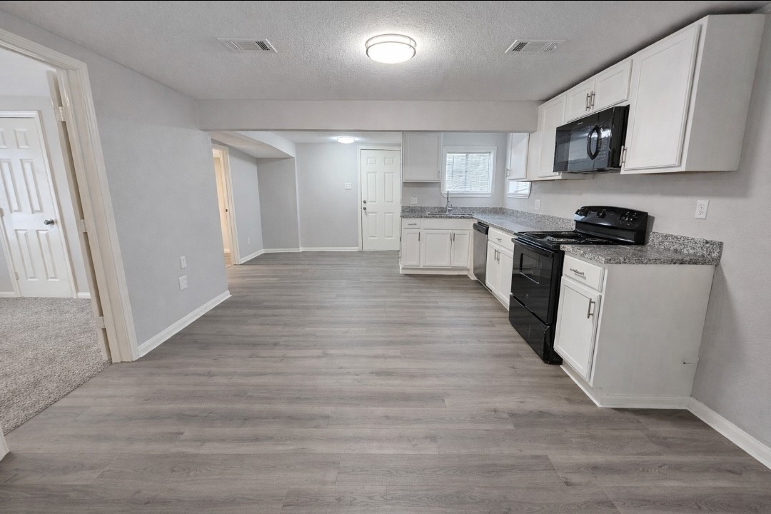 309 E Pine Daisetta, TX 77533 - Photo 5 of 23 a kitchen with stainless steel appliances granite countertop a stove top oven a sink a refrigerator white cabinets and wooden floor