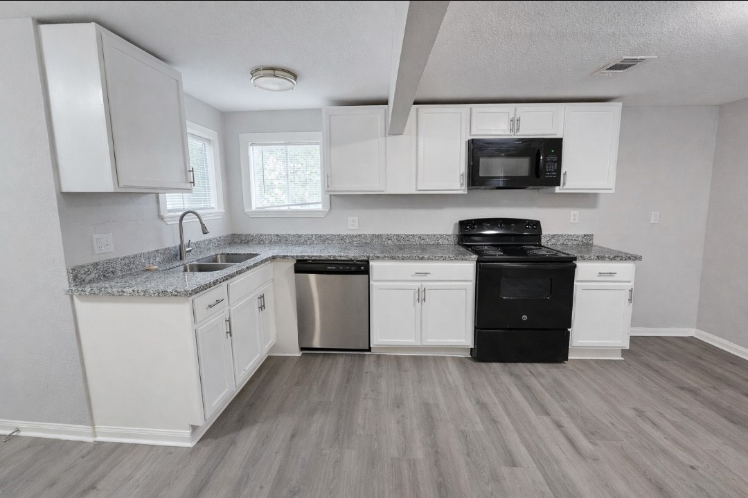 309 E Pine Daisetta, TX 77533 - Photo 6 of 23 a kitchen with granite countertop a sink dishwasher a stove and a microwave oven with cabinets