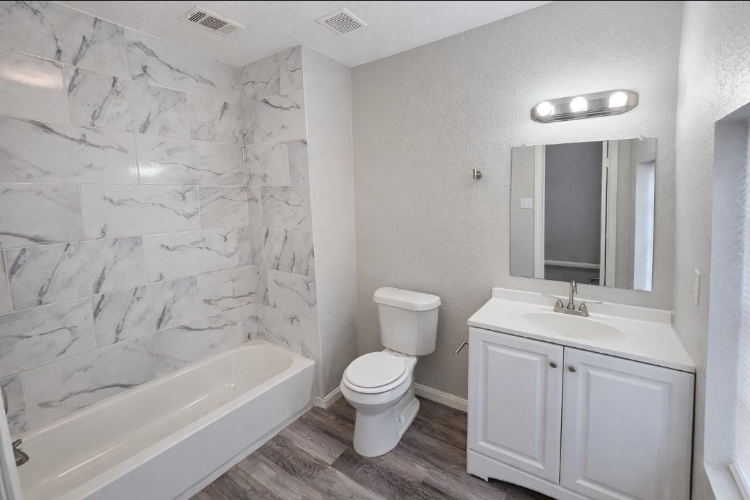 309 E Pine Daisetta, TX 77533 - Photo 9 of 23 a bathroom with a granite countertop sink a toilet and bathtub