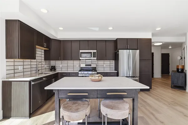 a kitchen with refrigerator a sink and chairs