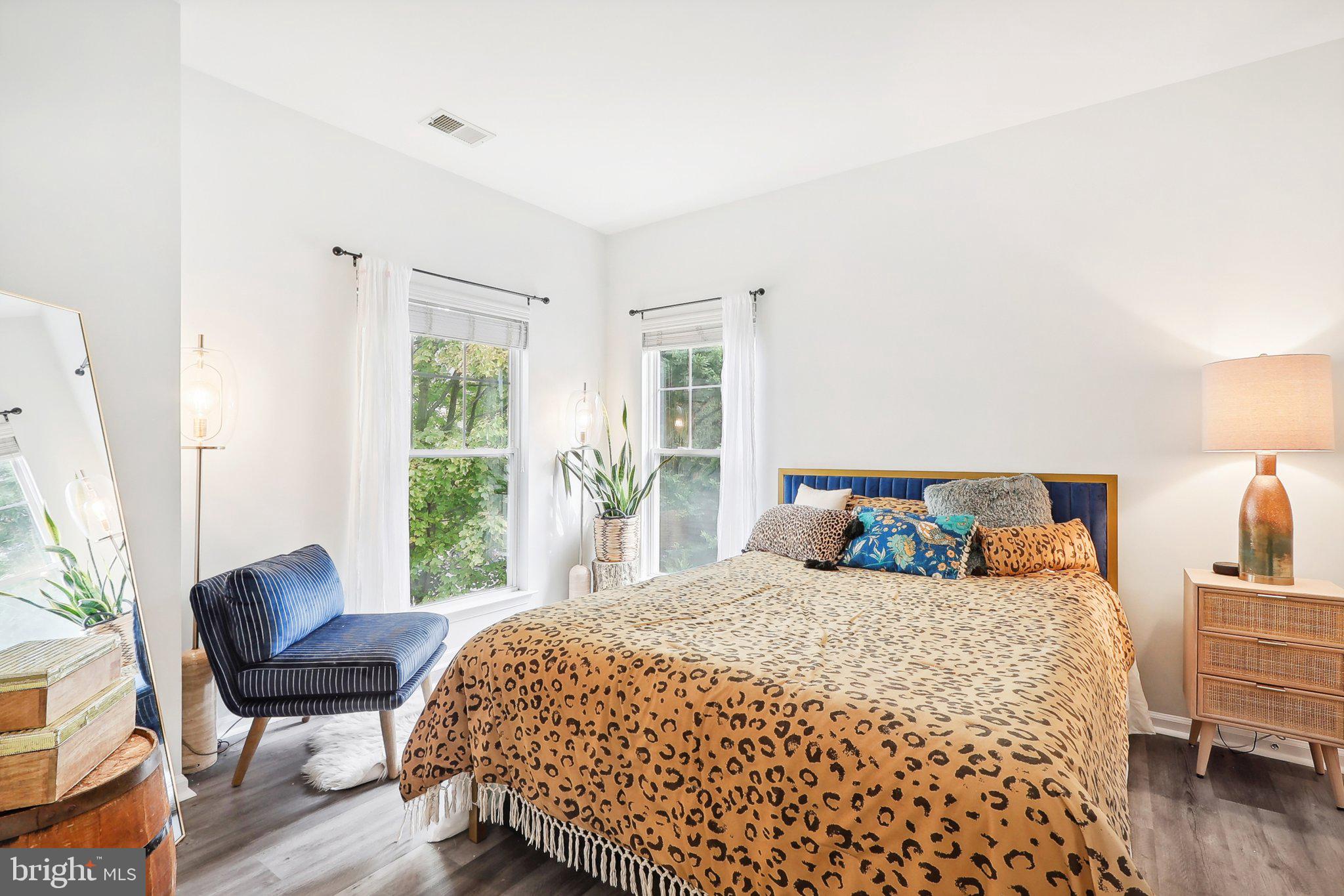 1516 North Point Drive, Unit 301 Reston, VA 20194 - Photo 22 of 31 a bedroom with a bed a lamp and a large window with wooden floor