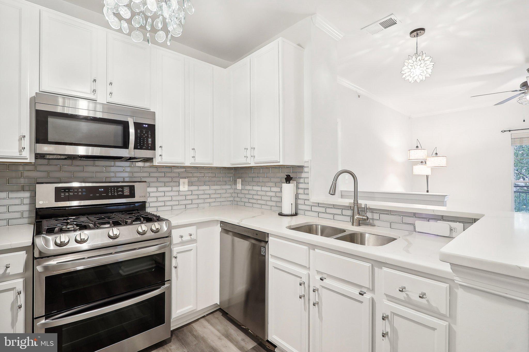1516 North Point Drive, Unit 301 Reston, VA 20194 - Photo 6 of 31 a kitchen with sink a microwave a stove and cabinets