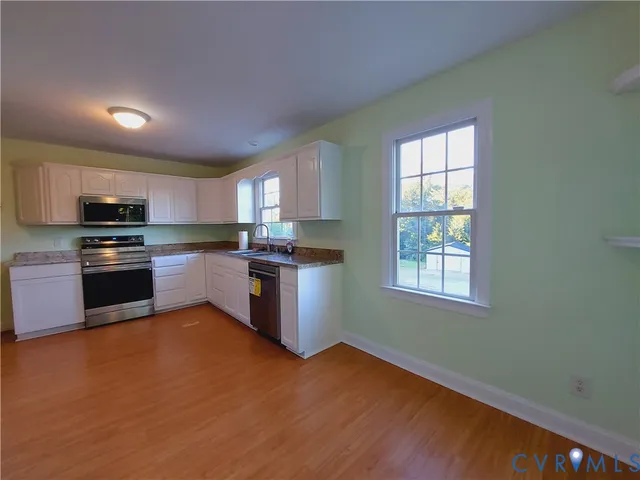 a kitchen with a refrigerator wooden floor and a window