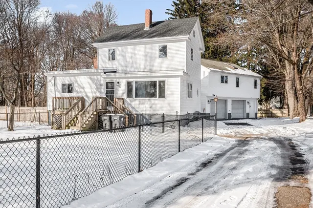 a view of a white house with wooden fence