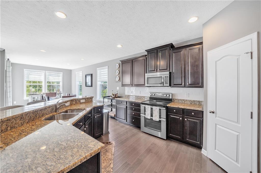 896 Ashley Road Gibsonia, PA 15044 - Photo 3 of 25 a kitchen with stainless steel appliances granite countertop wooden cabinets a sink dishwasher a stove and a refrigerator with wooden floor