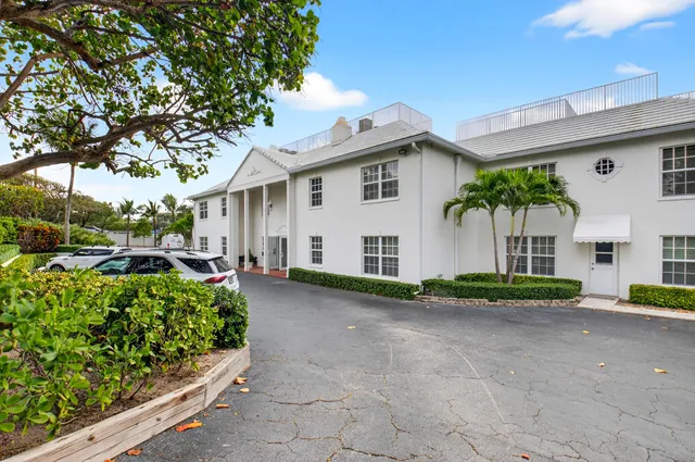 a view of a white house with a large space and a large tree