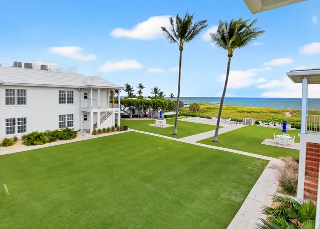 a view of a house with a big yard and palm trees