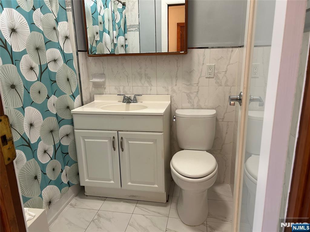 192 Kearny Avenue, Unit 2 Kearny, NJ 07032 - Photo 13 of 16 a bathroom with a sink and mirror with toilet