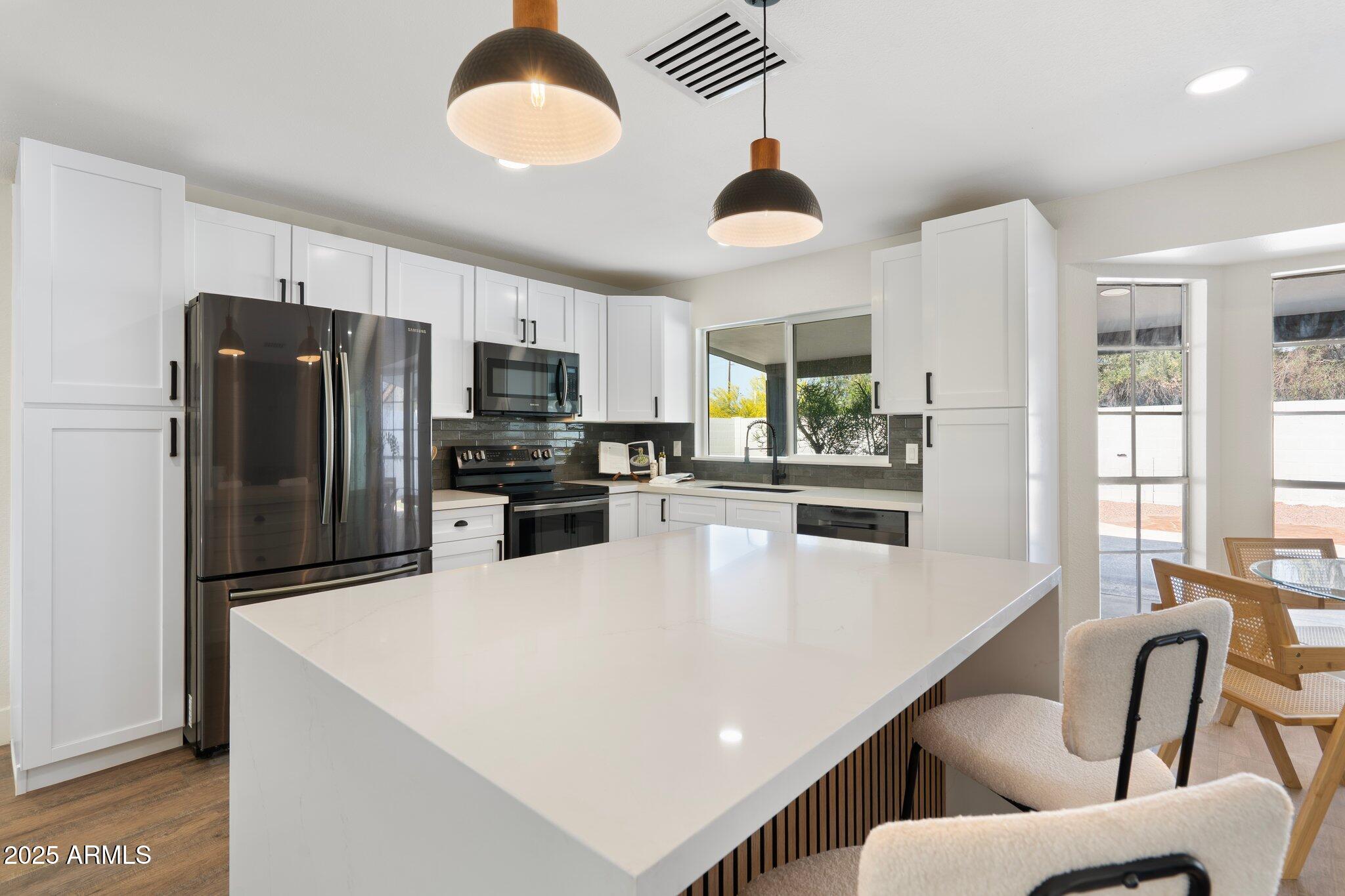 1721 North Apache Drive Chandler, AZ 85224 - Photo 2 of 22 a kitchen with stainless steel appliances a refrigerator a stove a sink a dining table and chairs with wooden floor