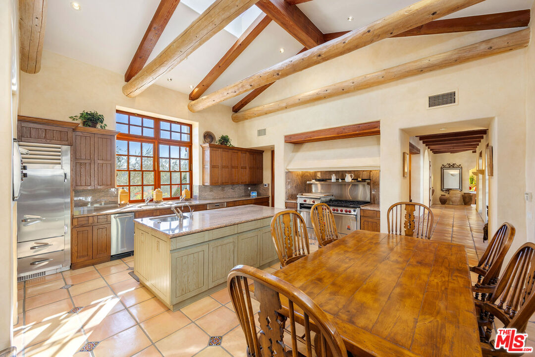 25127 Jim Bridger Road Hidden Hills, CA 91302 - Photo 13 of 50 a kitchen with stainless steel appliances granite countertop a stove a refrigerator a dining table and chairs with wooden floor