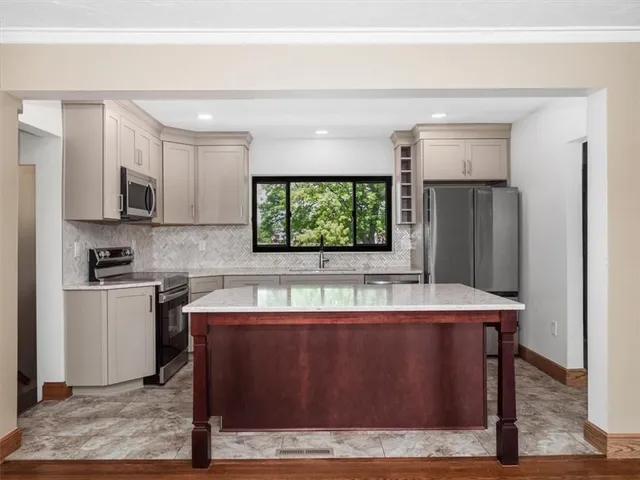 a room with a large window and kitchen view